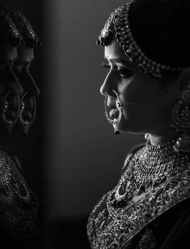 Riya in bridal jewellery, her profile mirrored in a reflection, in black and white